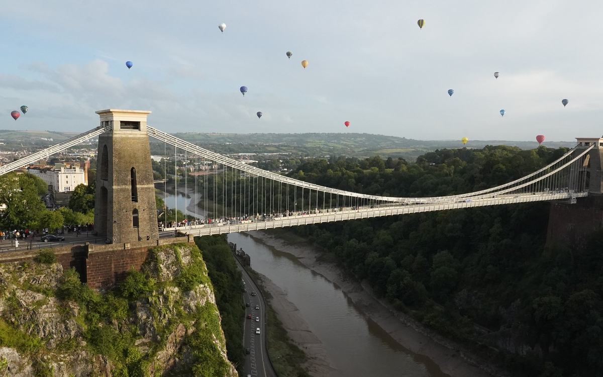 Hot air balloons from the Bristol International Balloon Fiesta mass ascent in the sky beyond the Clifton Suspension Bridge