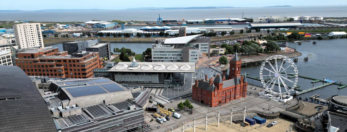 Aerial view of Cardiff Bay with the red-brick Pierhead Building, the Senedd, a Ferris wheel and Roald Dahl Plass