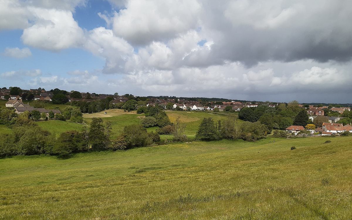 View from a hillside across the River Chew valley towards the houses of Keynsham under a partly cloudy sky
