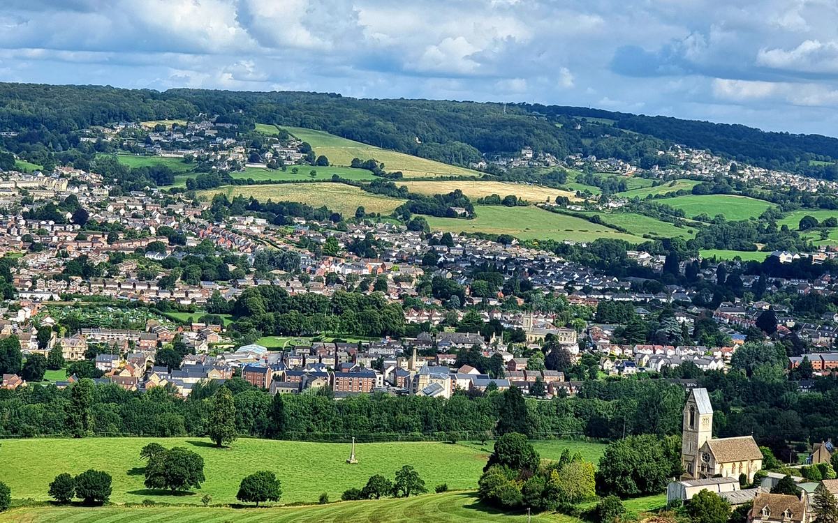 View from Selsley Common towards Stroud: houses across the valley and hillsides, green fields and a village church
