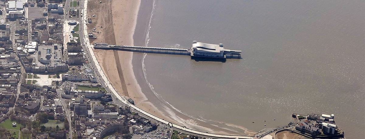 Aerial view of Weston-super-Mare seafront at low tide, with the Grand Pier, sandy beach and Knightstone Island